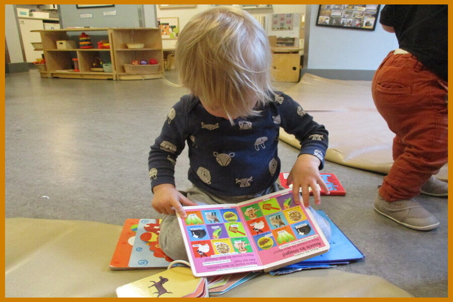 A child looking at a book while sitting on a mat