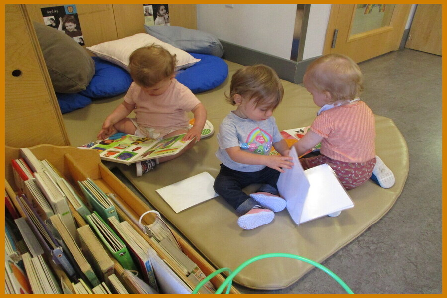 Young children looking at books while sitting on a mat