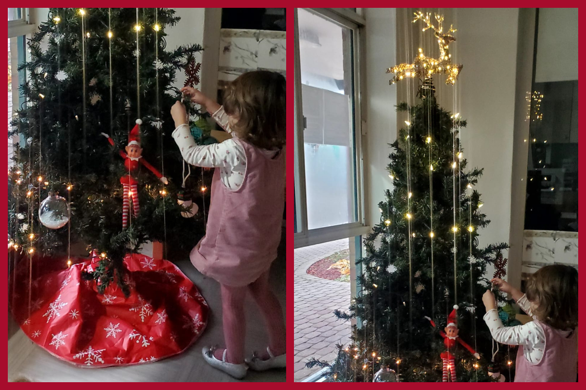 A child placing a decoration on a holiday tree that is our 'Giving Tree'