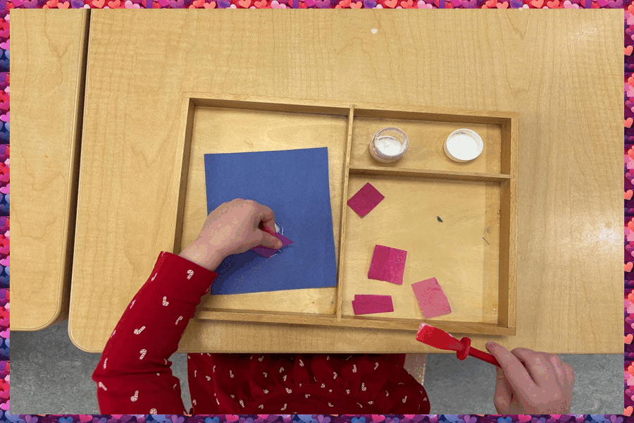 A child gluing pieces of tissue onto a piece of construction paper