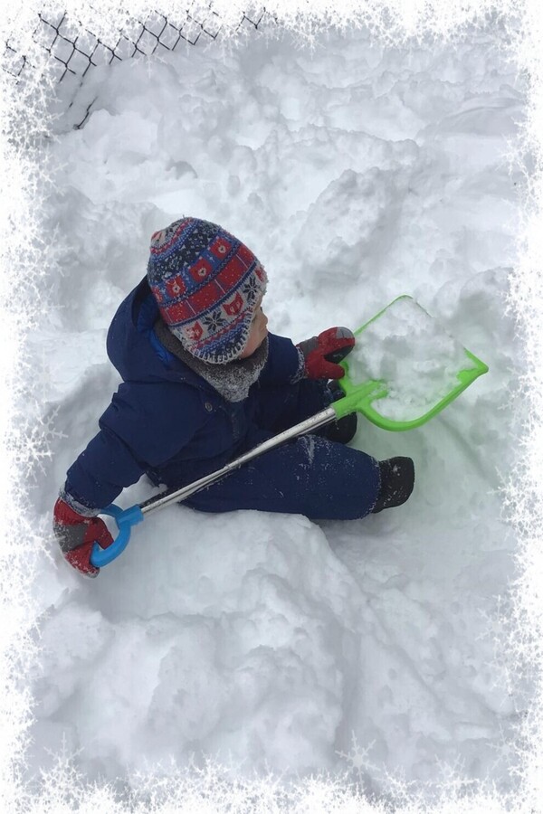 A child sitting with a shovel of snow