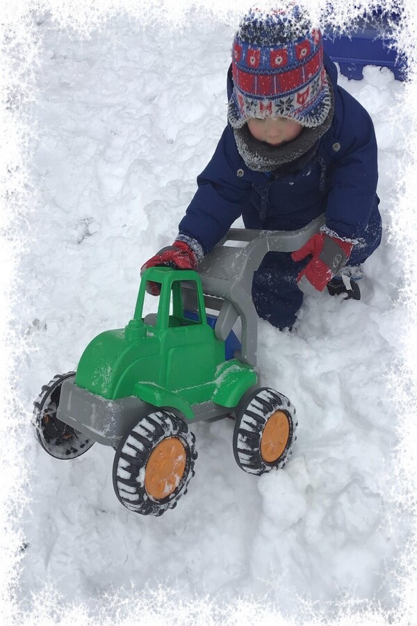 A child rolling a truck in the snow